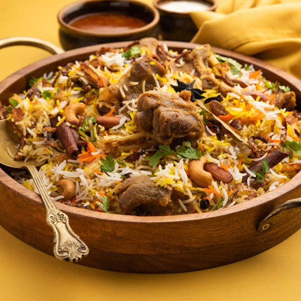 Close-up of Kadai Indian Kitchen's lamb biryani, garnished with cashews, almonds, and spices, in a wooden bowl.